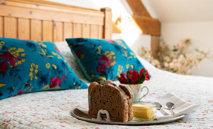 Double bed with breakfast on a tray and flowers.